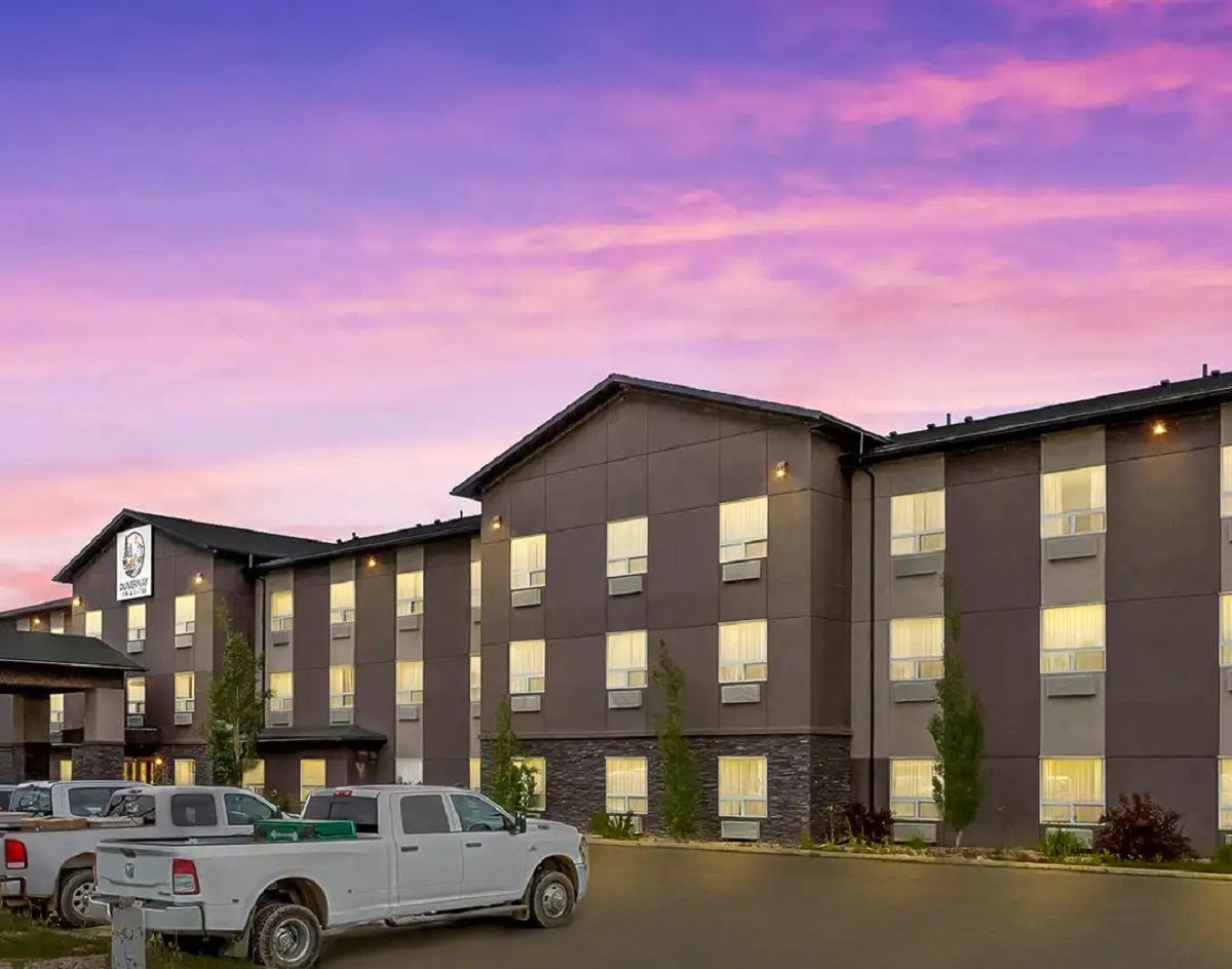 Modern hotel exterior at sunset with parked white trucks.
