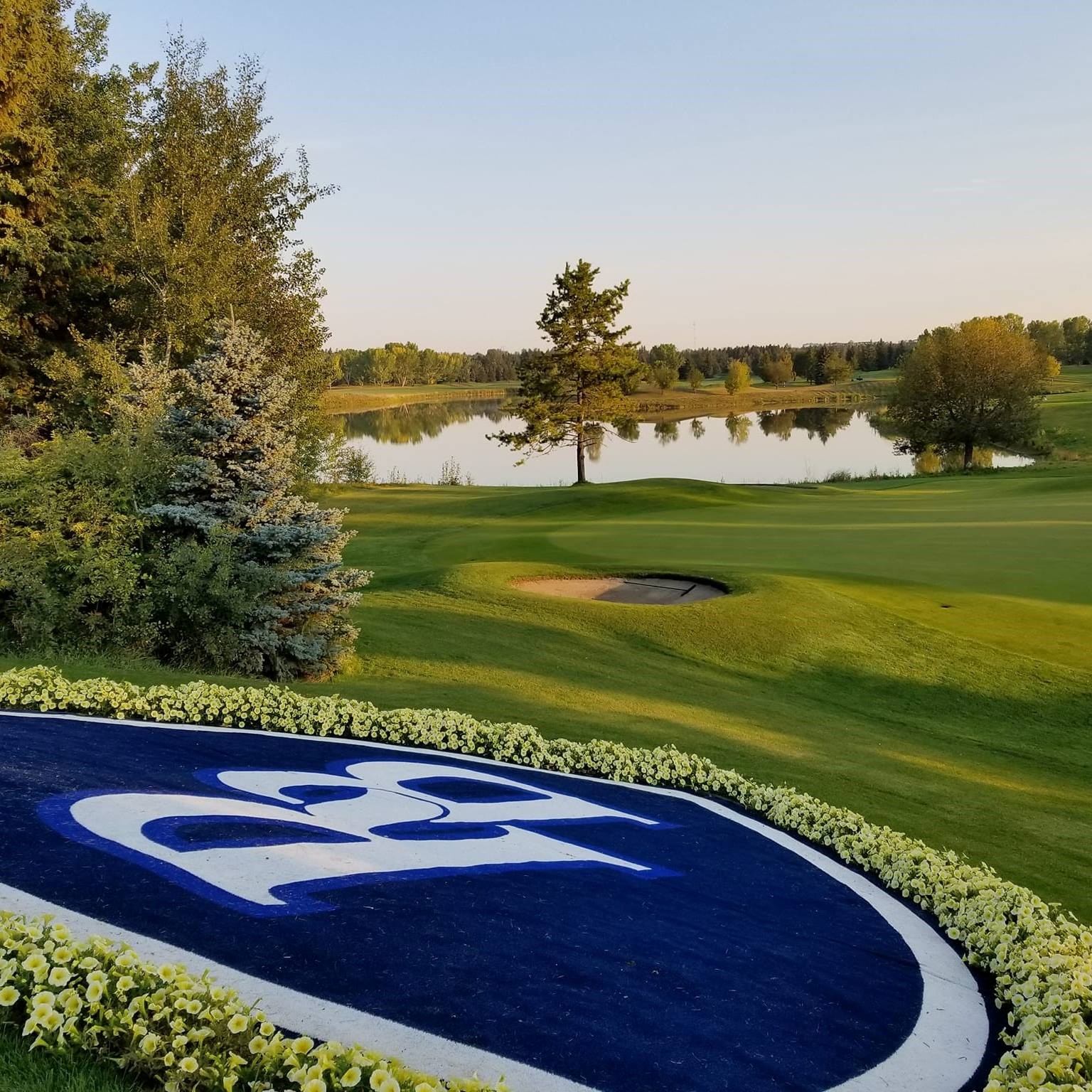 Scenic golf course with emblem “21,” flowers, and water feature.