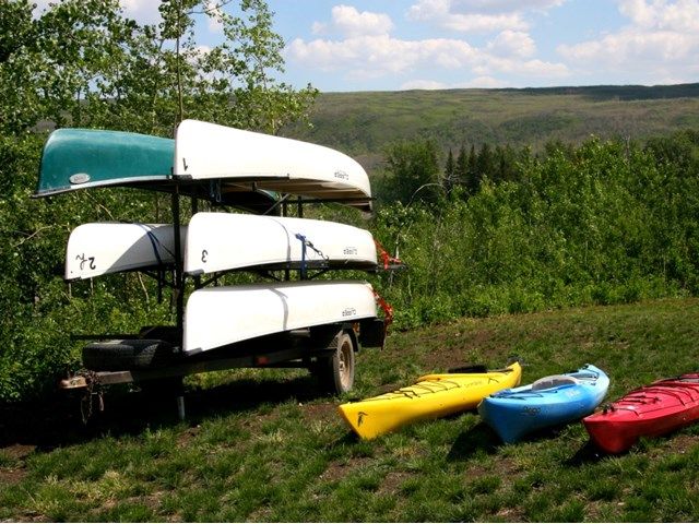 Canoes and kayaks sitting on grass.