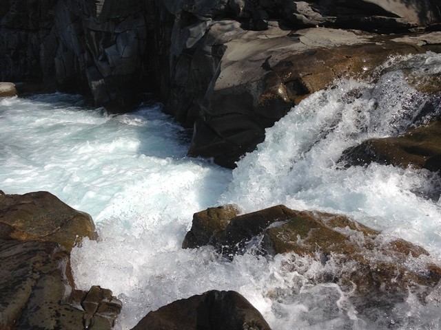White water rapids crashing over rocks with foamy water splashing around.
