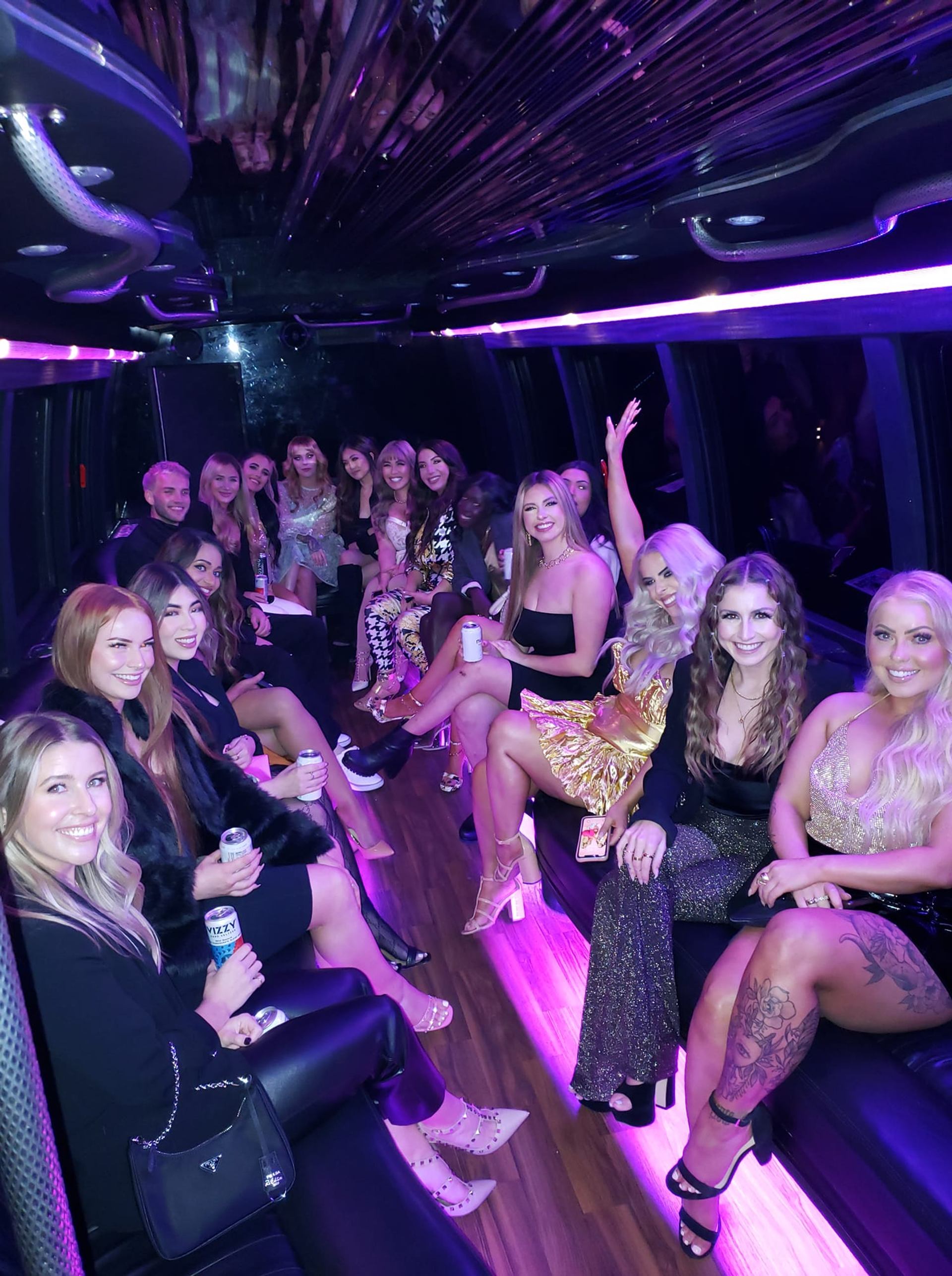 People partying inside a bus with glowing purple lights.