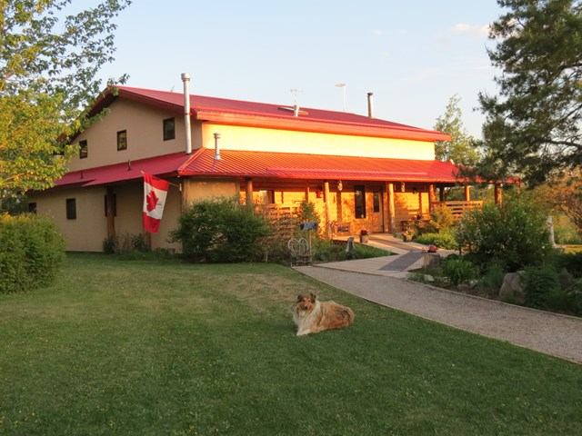 Lodge with red roof, Canadian flag, and a dog resting on the green lawn