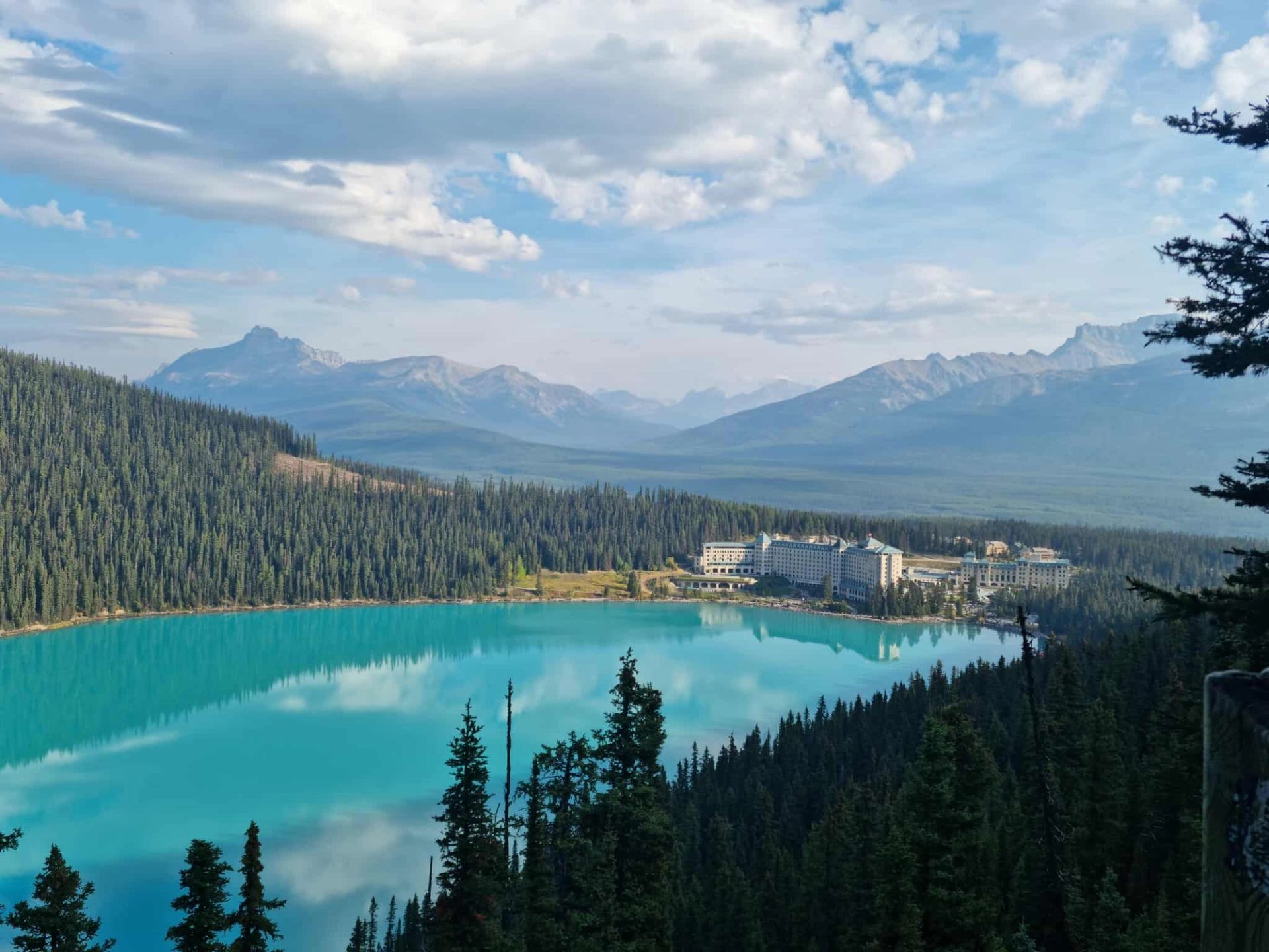 Lake Louise and surrounding forest with hotel below mountain peaks.
