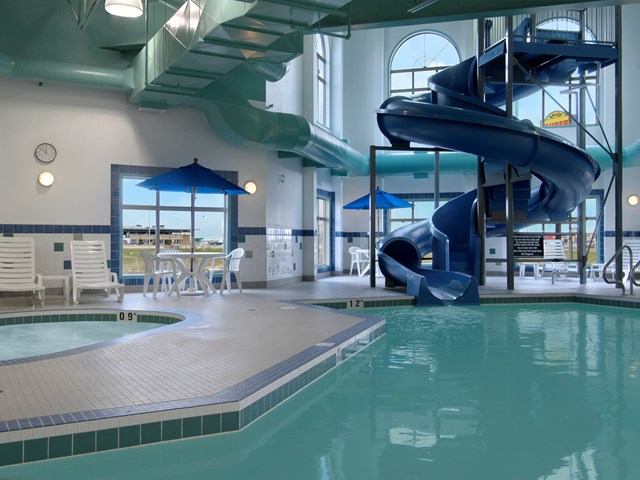 Indoor pool with spiral slide, lounge chairs, and large windows.