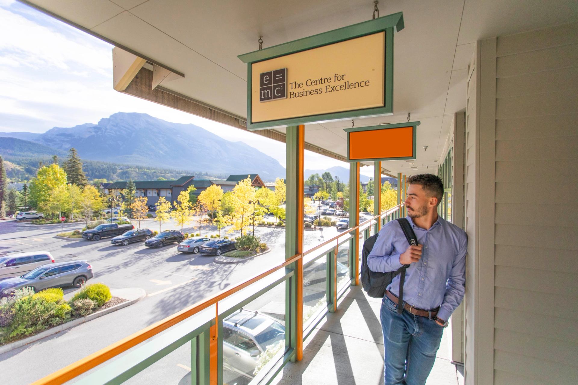 Person walking onto a balcony at a business centre with mountain and parking lot views.