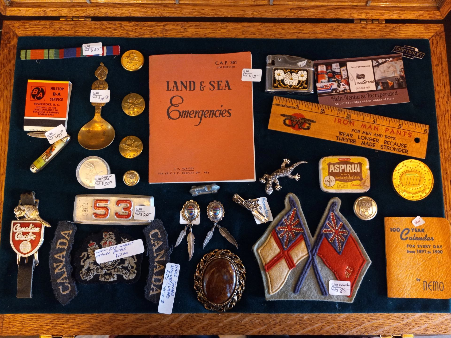 Display case with assorted vintage Canadian memorabilia, badges, coins, and booklets.