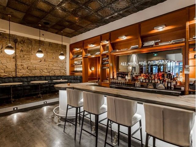 Stylish lounge with bar seating, warm lighting, and exposed brick and wood accents.