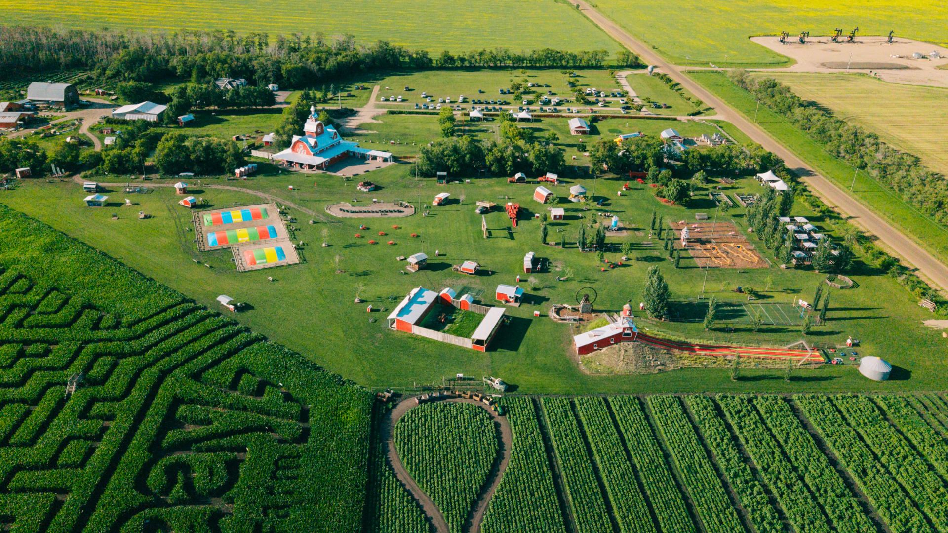 Aerial view of farm attraction with corn maze, barns, play areas and parking lot.