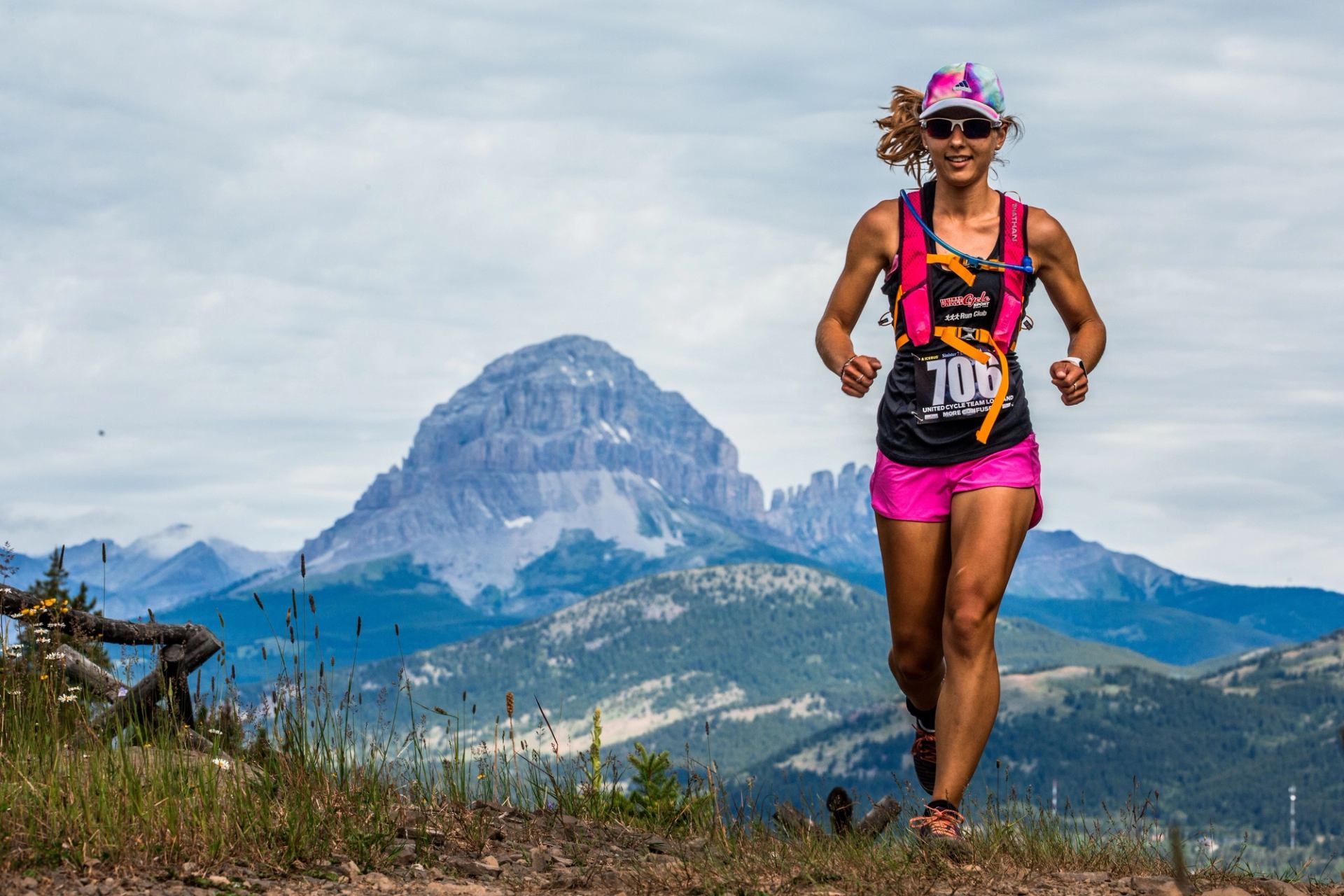 Runner in pink races through mountain terrain with bib number 708.
