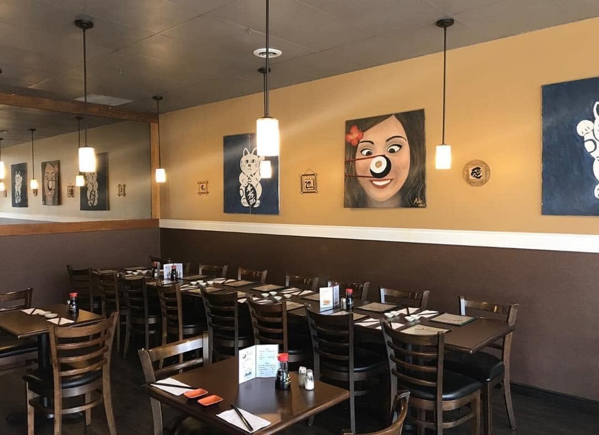 Restaurant dining room with set tables, pendant lights and colourful wall art.