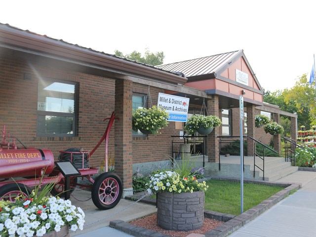 Brick museum with flowers and vintage fire truck at Millet Visitor Centre.