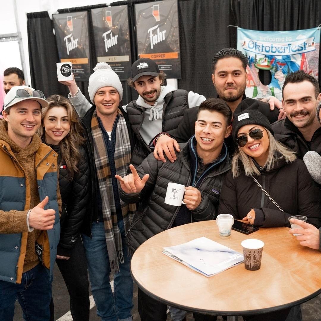 Group of friends smiling and holding drinks at a table during the Edmonton Craft Beer Festival.