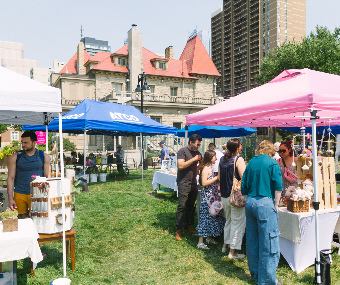 Outdoor market at Lougheed House with tents, vendors, and visitors in a city setting.