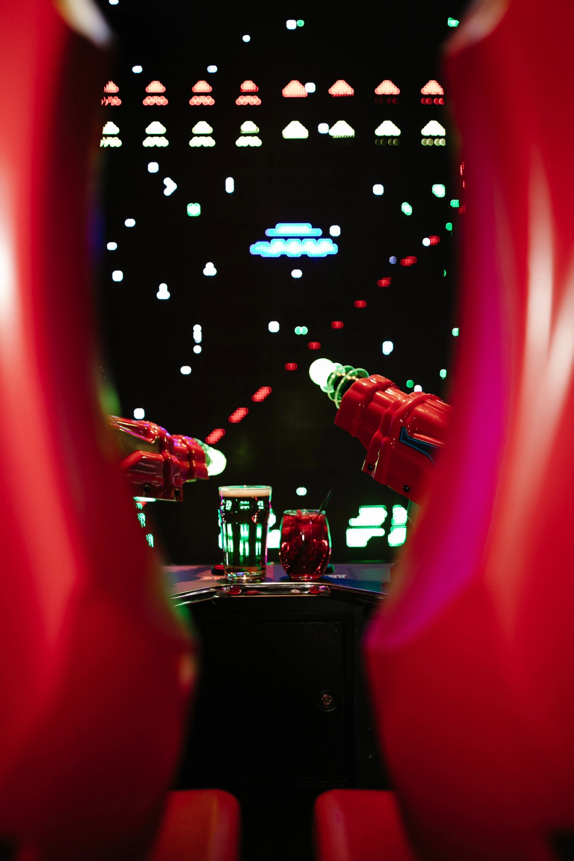 Bowling lane display lights and red bowling ball return, seen through red curtains.