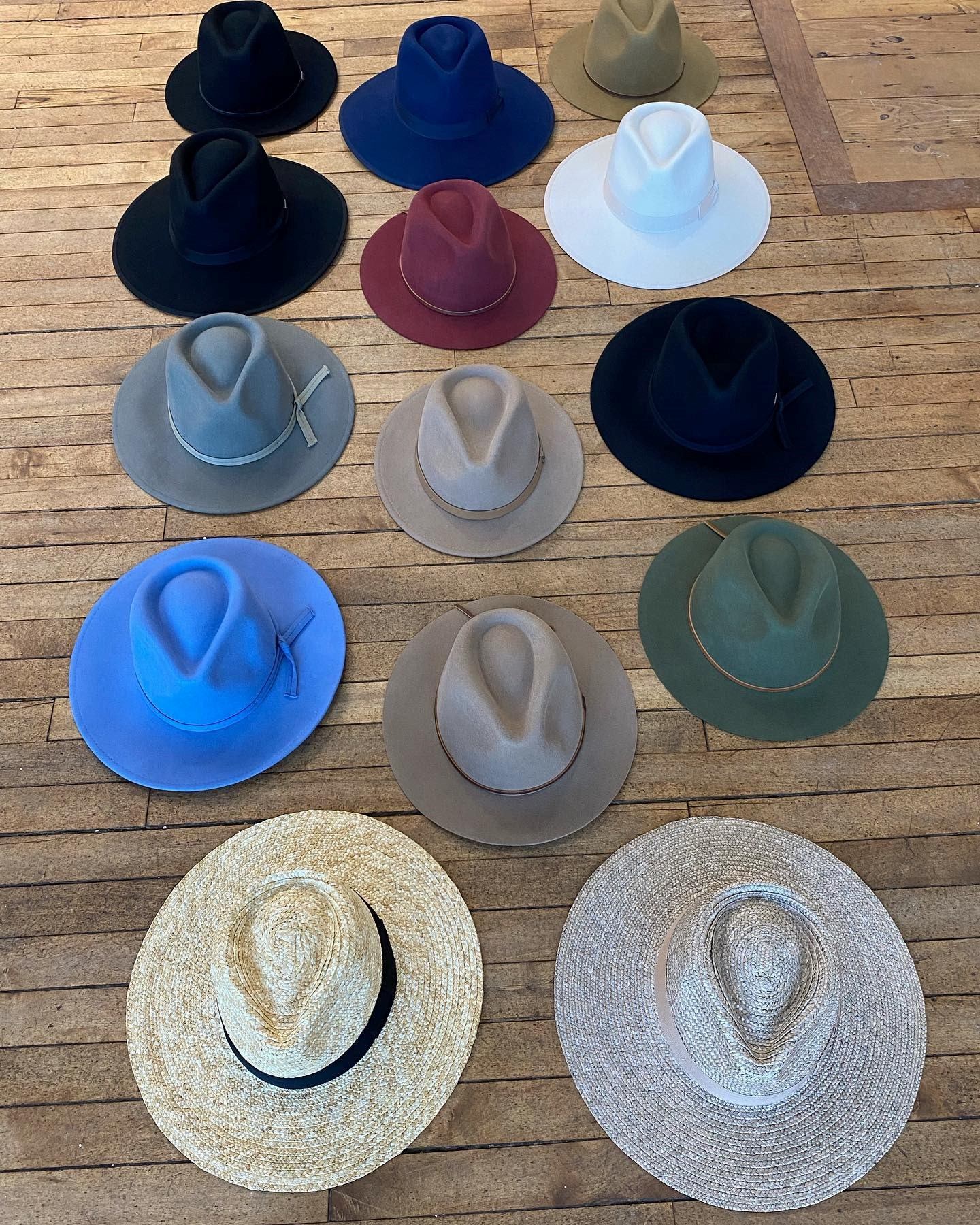 Men’s hats displayed on wooden boards, including black, blue, white, and straw styles.
