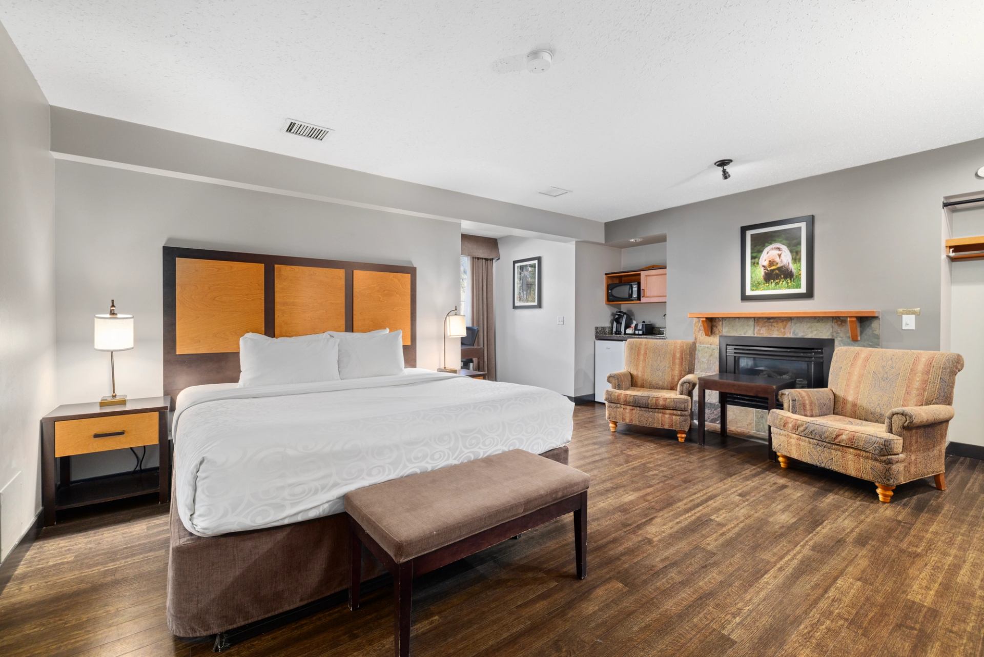 Hotel room with a king size bed, with a small seating area to the right and a fireplace.