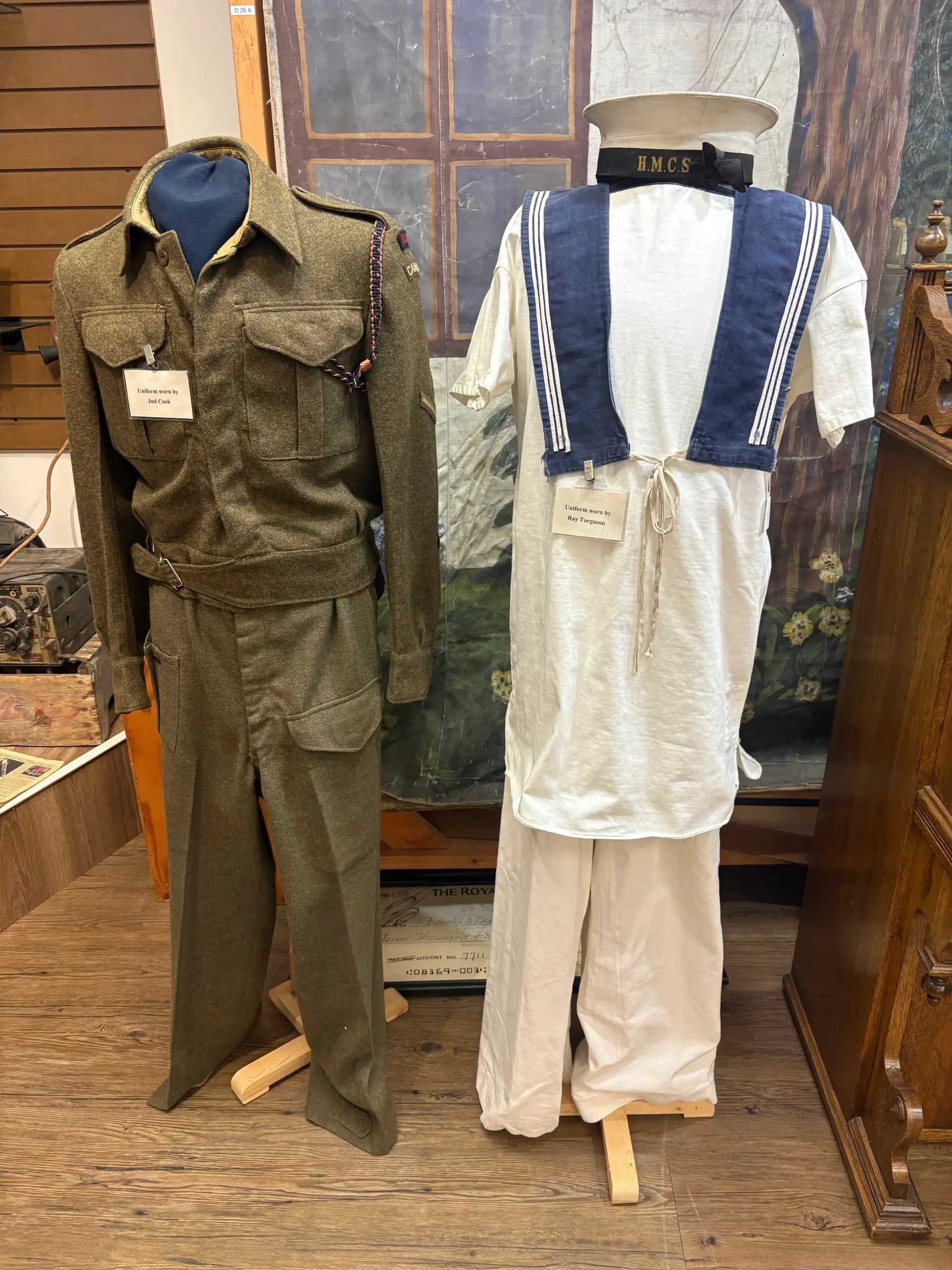 Museum display of army uniform and HMCS sailor uniform on mannequins.