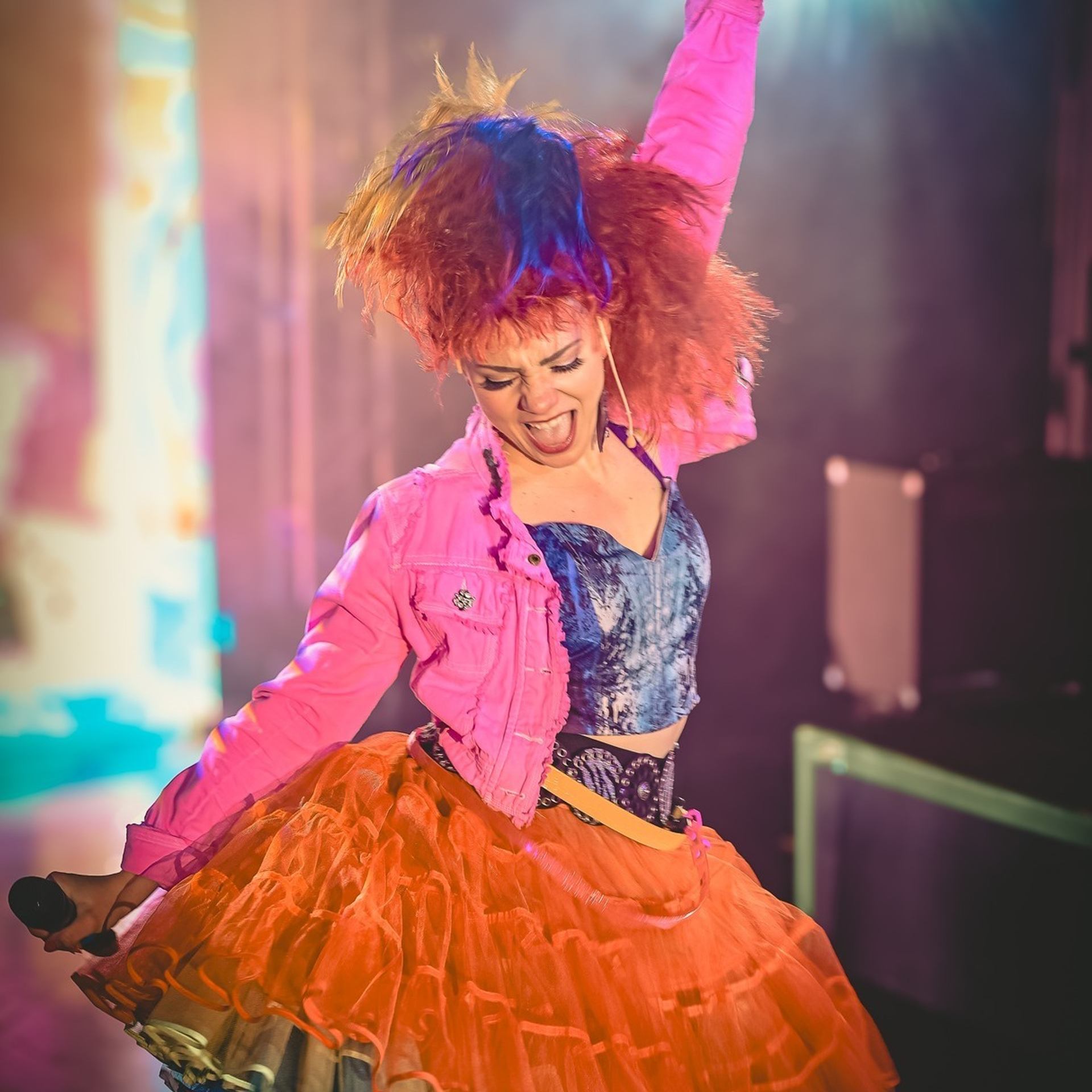 Colorful 80s outfit with tutu and jacket under stage lights.