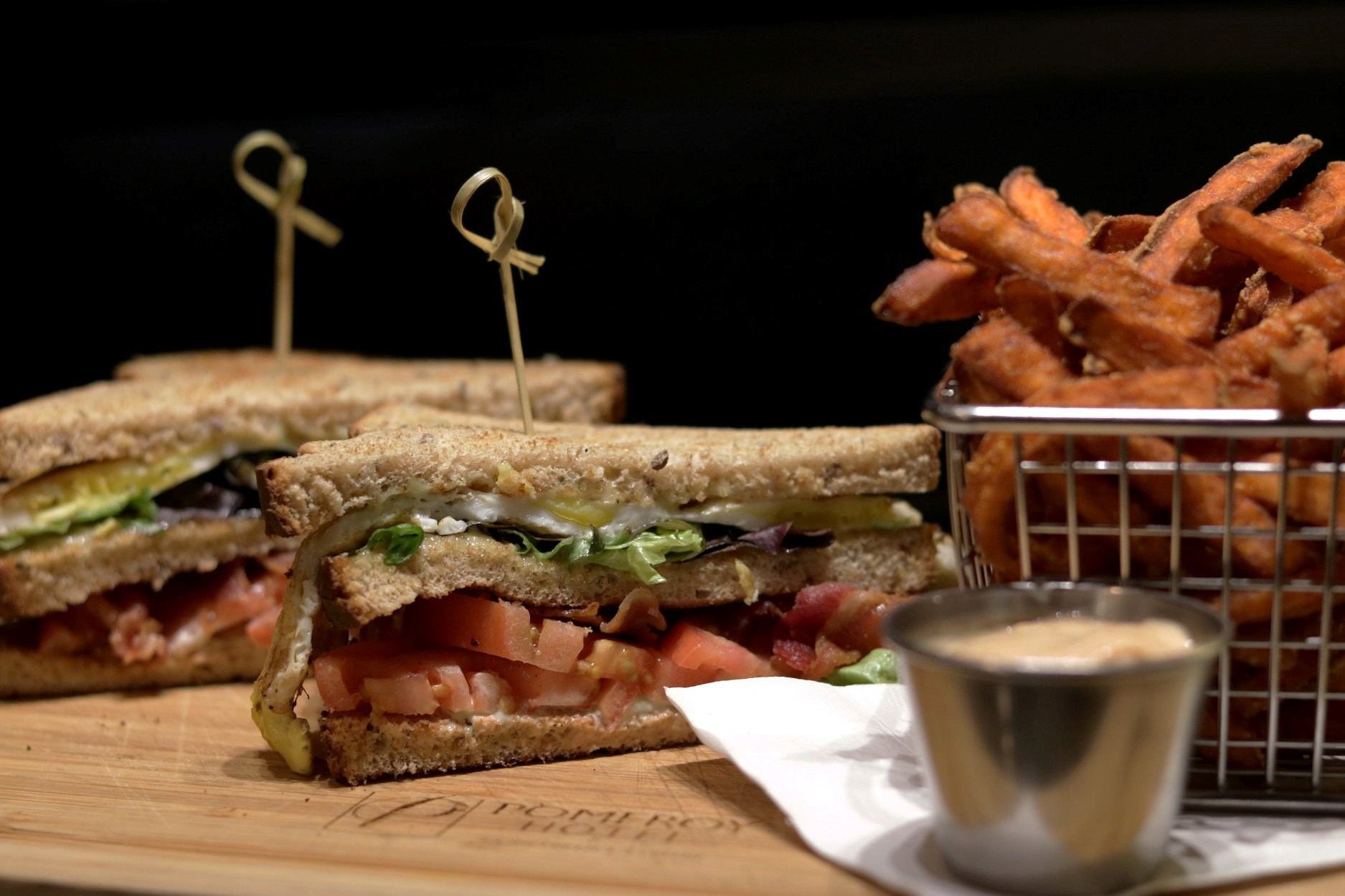 Sandwich halves with layered fillings, served with sweet potato fries and dip.