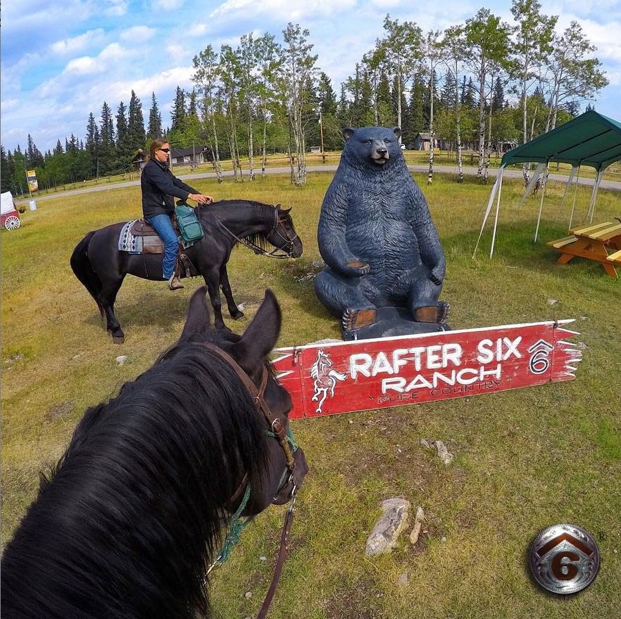 Horseback riders near a bear statue at Rafter Six Ranch Resort.