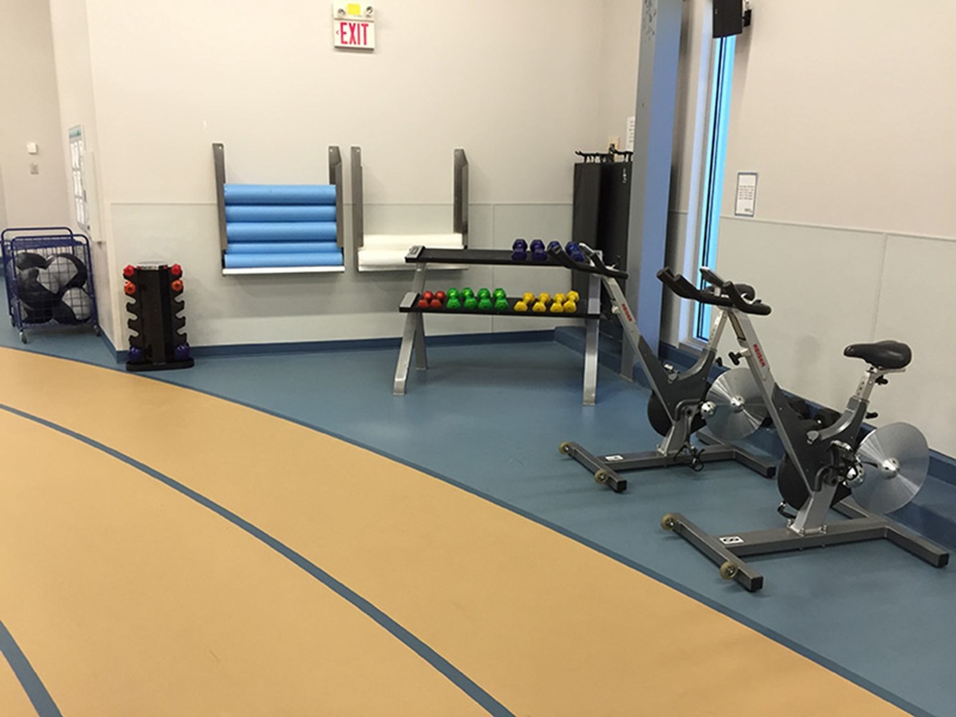 Indoor fitness room with exercise bikes, dumbbells, foam rollers and an indoor track.