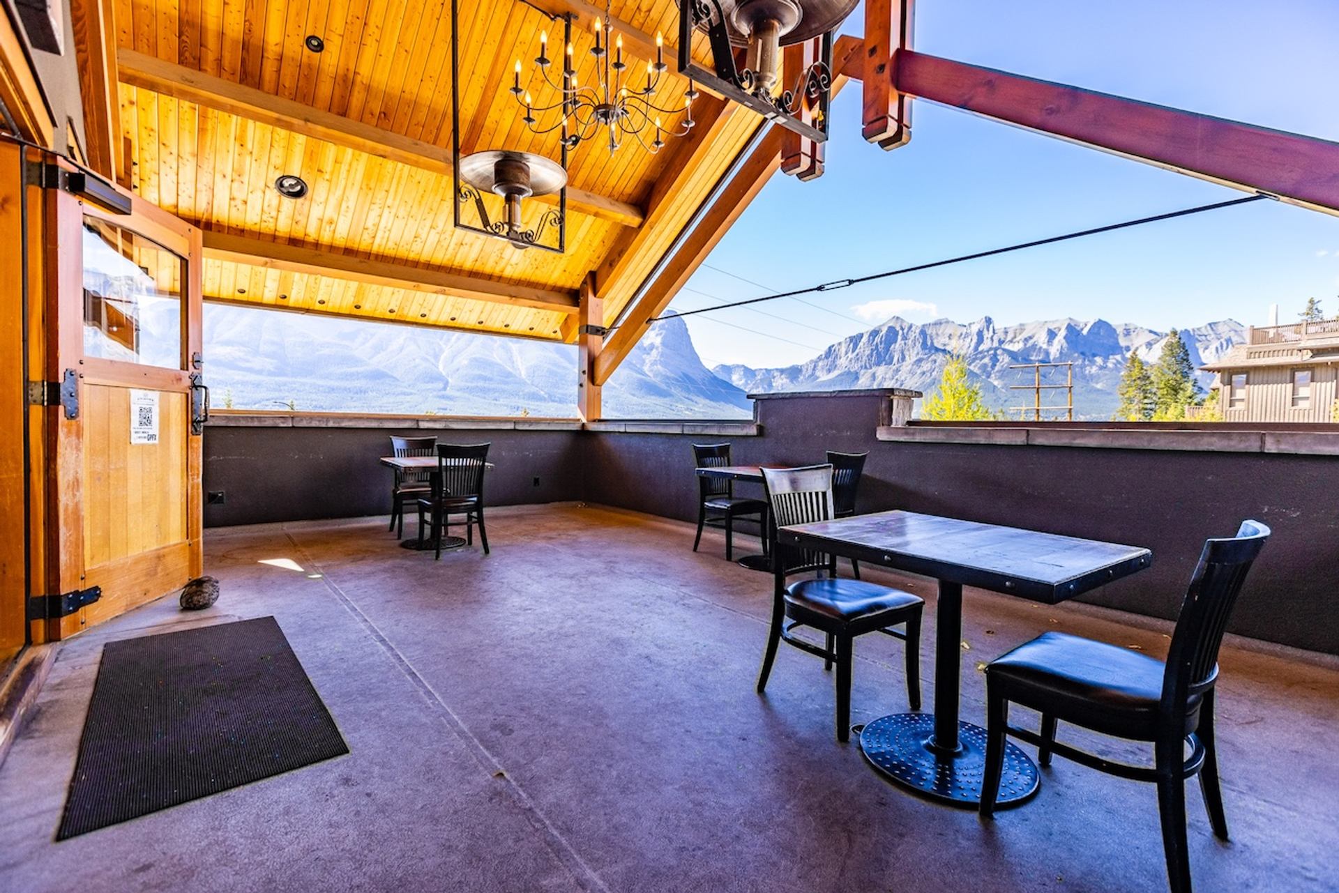 Covered patio with tables and chairs overlooking a wide view of mountain ridges.