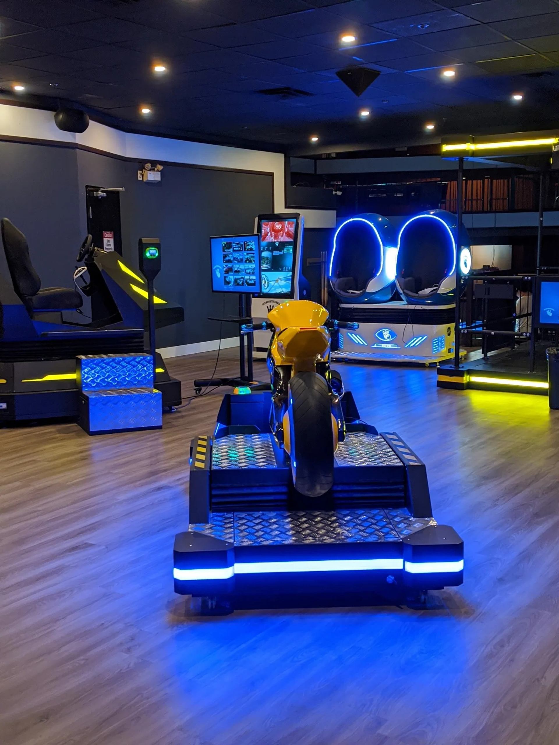 Virtual reality arcade with motorcycle simulator, glowing blue lights and futuristic gaming seats.