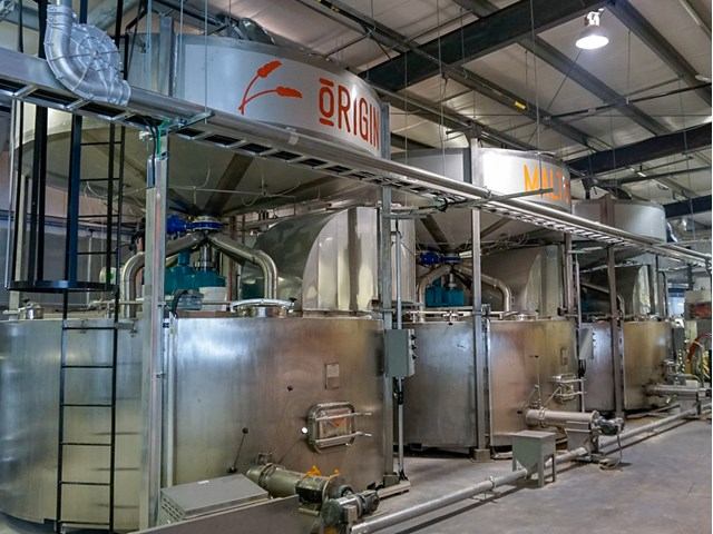 Factory interior with large tanks and machinery, showcasing an active industrial production environment.