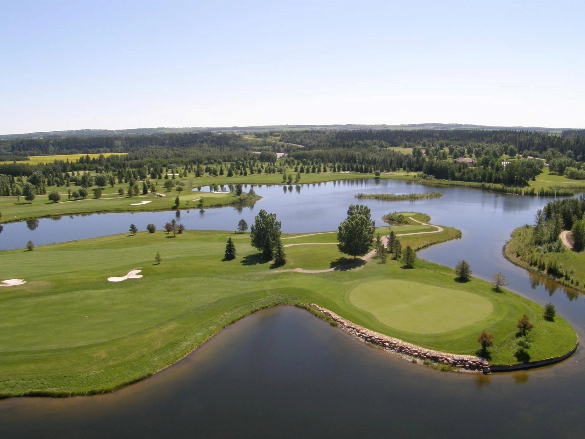 Aerial view of golf course with fairways, bunkers, and water features.