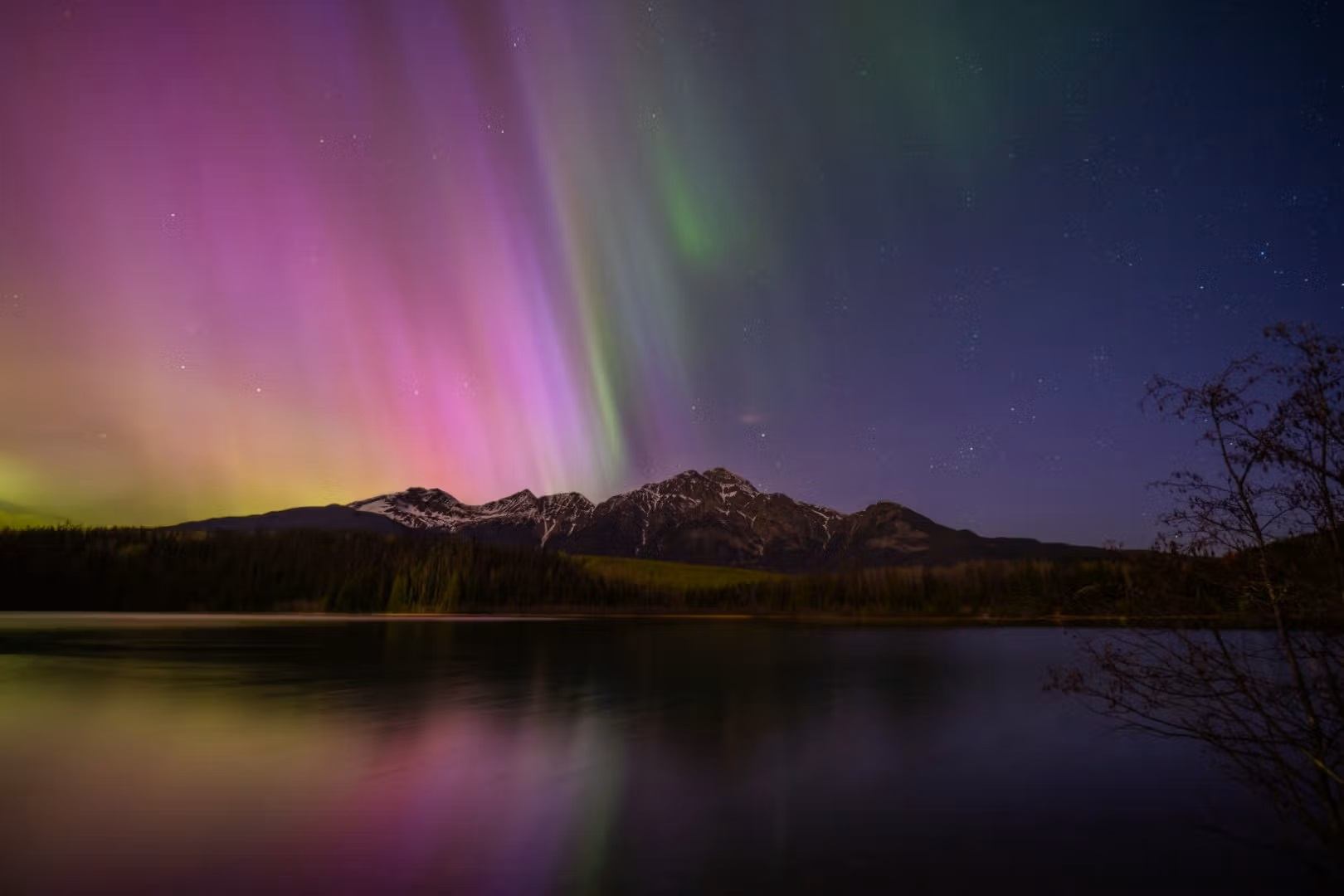 The Aurora Borealis shimmers above the Canadian Rockies.