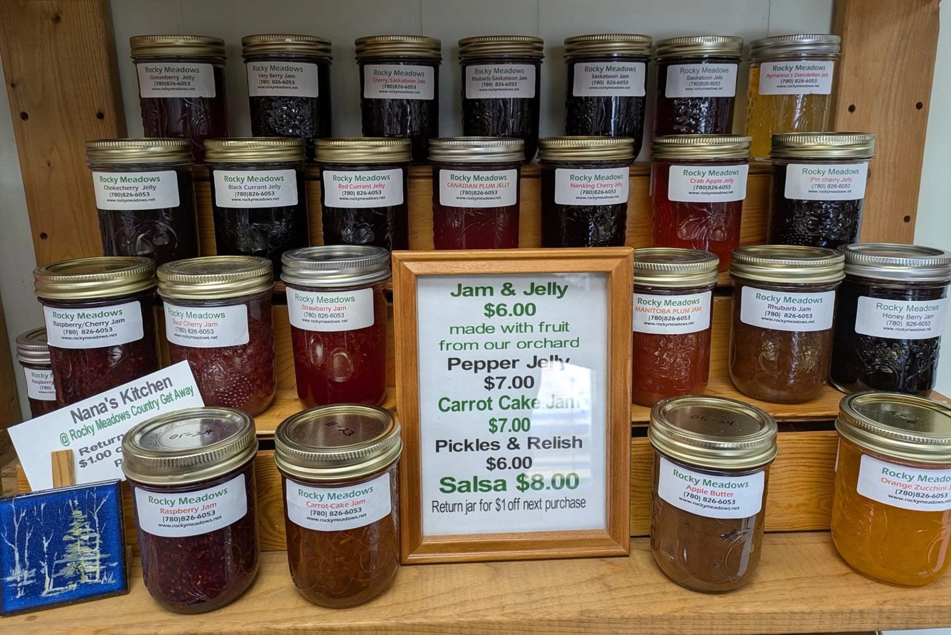 Shelves display jars of homemade jams, jellies, pickles, salsa, and preserves in various flavors.