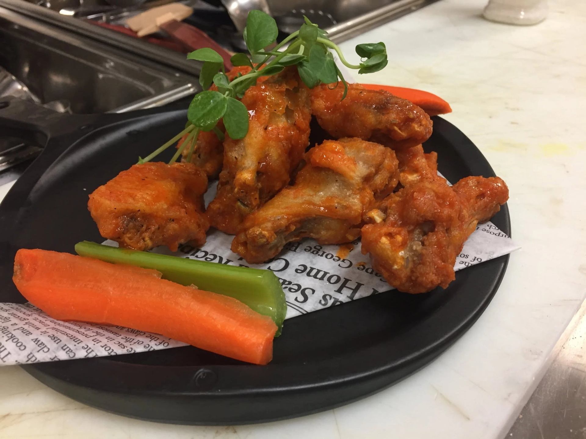 West 67 Lounge & Grill serves saucy chicken wings with fresh celery, carrots, and greens.