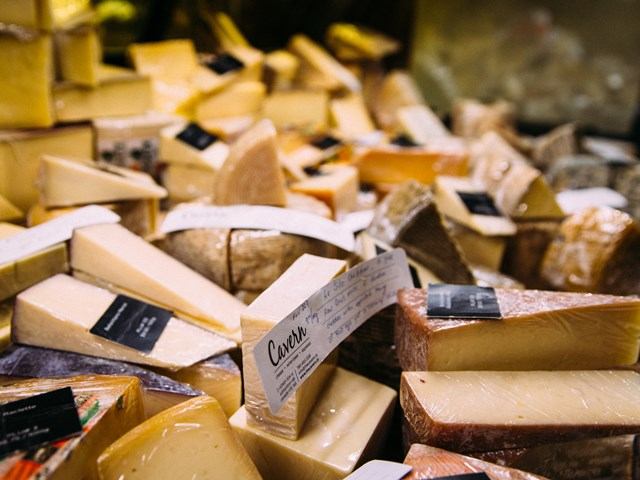 Assorted cheese wedges with labels displayed in a market-style setting.