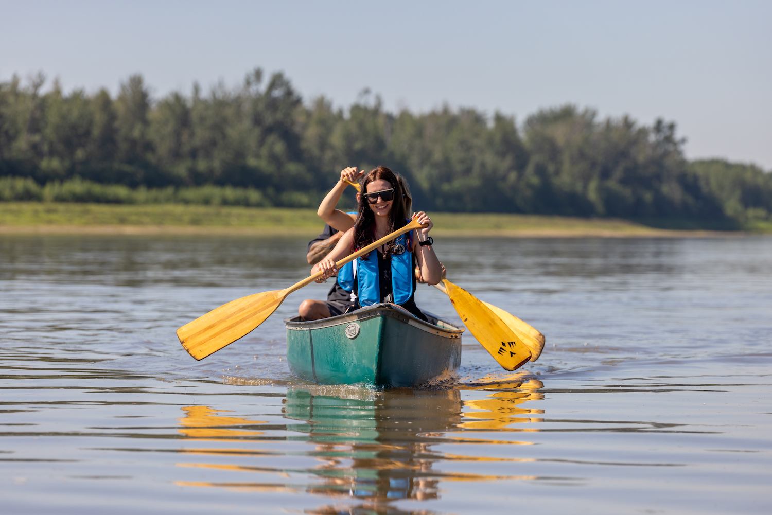 Peace River Adventures canoe ride with two people paddling on calm water surrounded by trees.