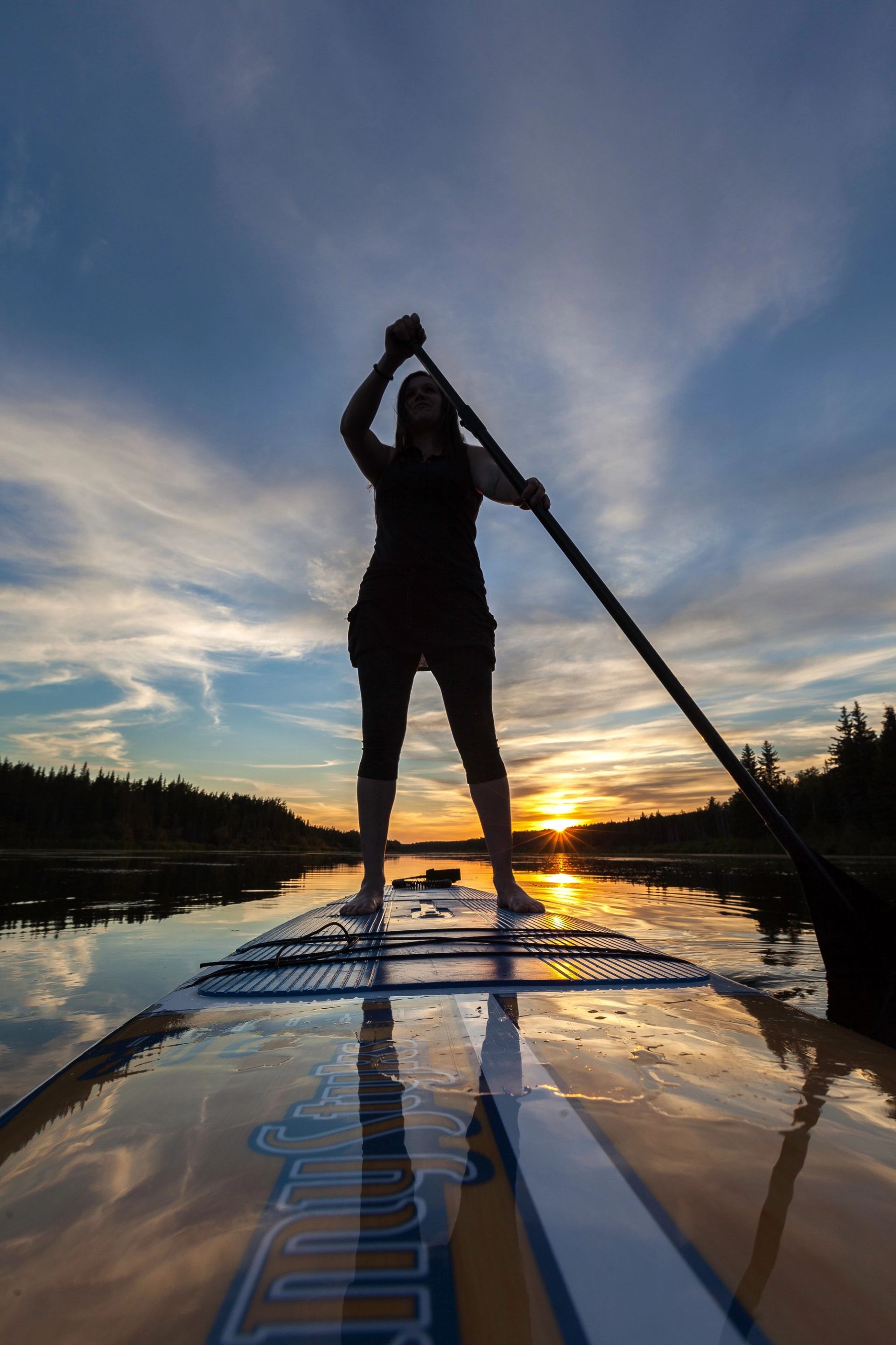 Peace River Adventures paddleboarding at sunset on calm water with colorful sky.