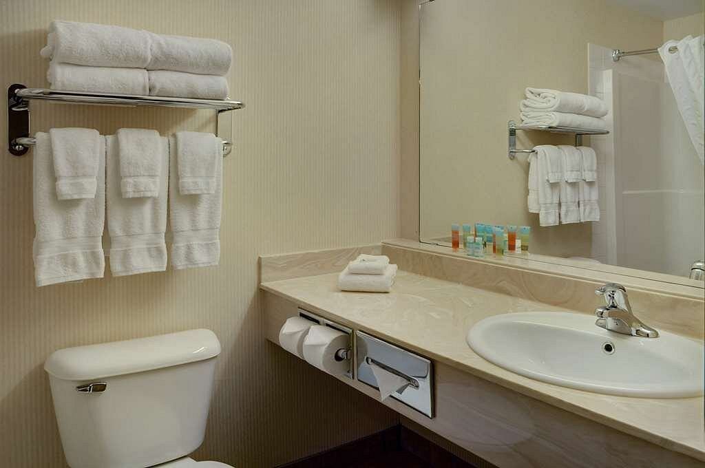 Bathroom with sink, mirror, and neatly arranged towels.
