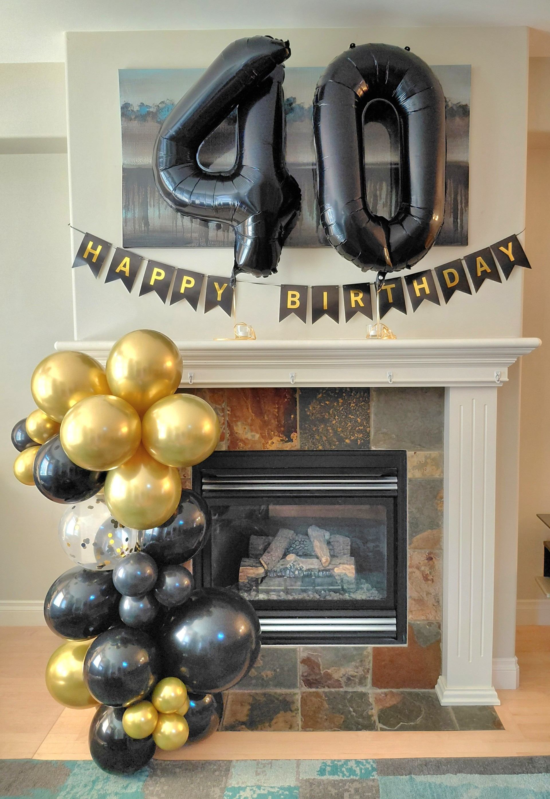 Fireplace decorated with large 40 balloons, Happy Birthday banner and gold, black balloons.