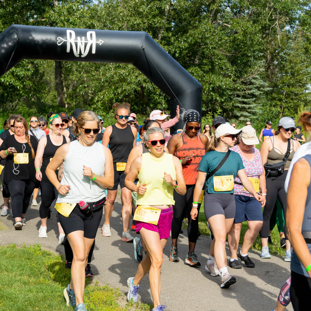 Participants walking and running under a start arch during the Rise run, yoga, and meditation event.