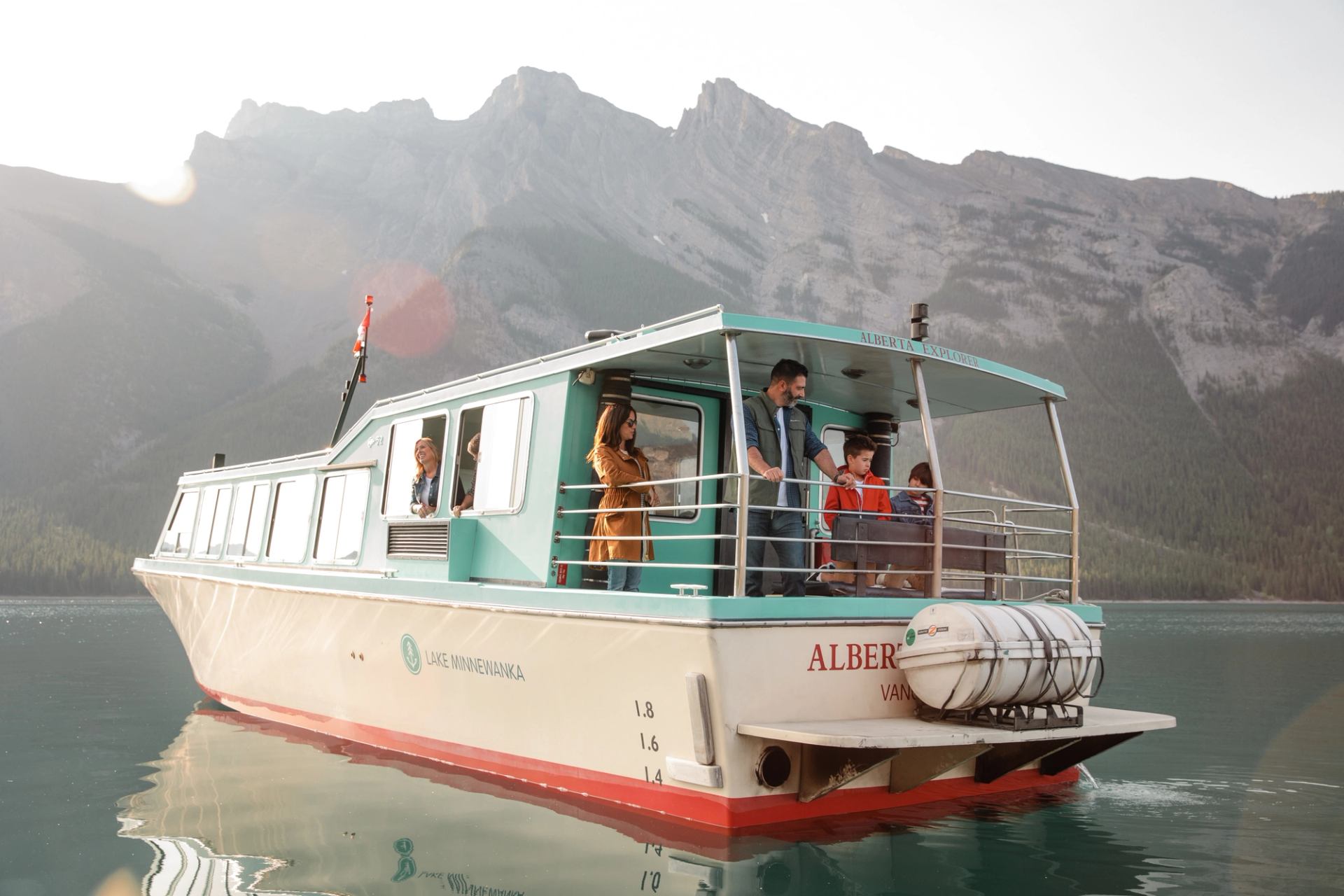 A family on a boat tour on a lake with mountains in the background.