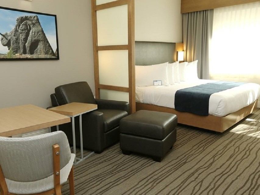 Hotel room with bed, armchair, ottoman, and small table at Best Western Plus.