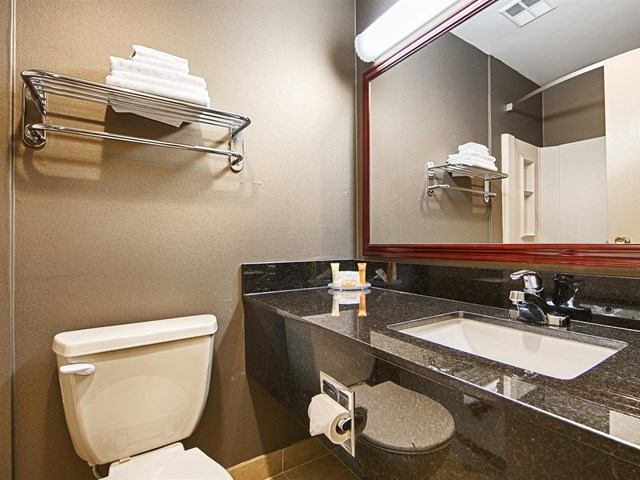 Modern hotel bathroom with granite countertop, sink, and wall mirror.