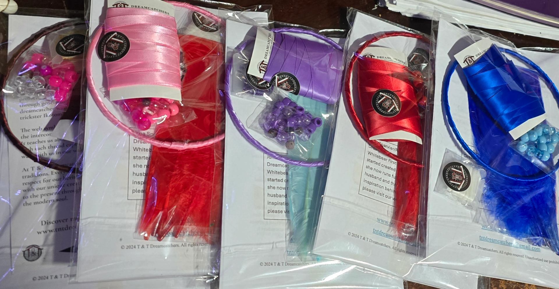 Packaged dreamcatcher craft kits with colourful hoops, ribbons, beads and feathers on papers.