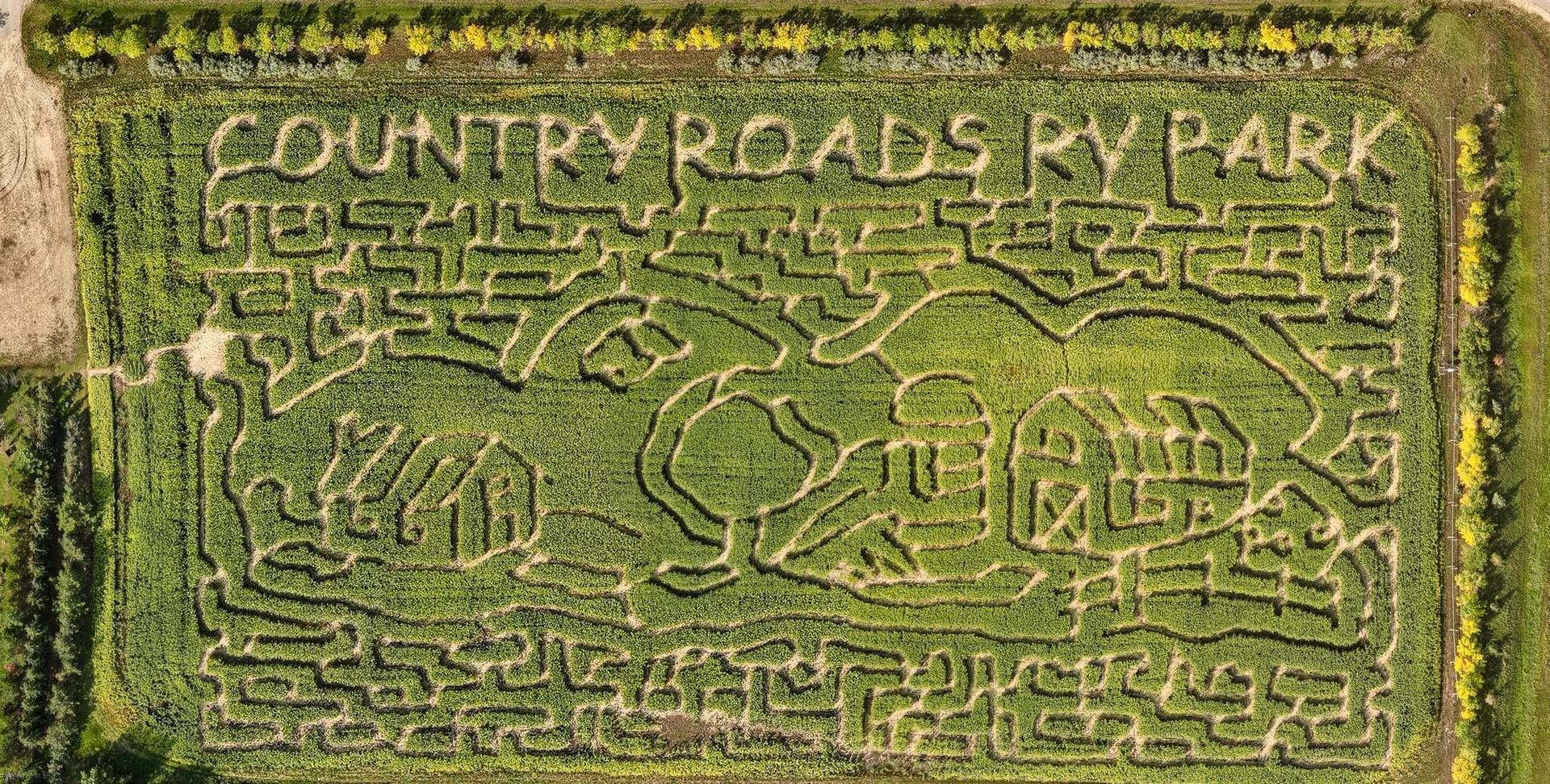 Aerial view of corn maze spelling COUNTRY ROADS RV PARK with barn and tree shapes.