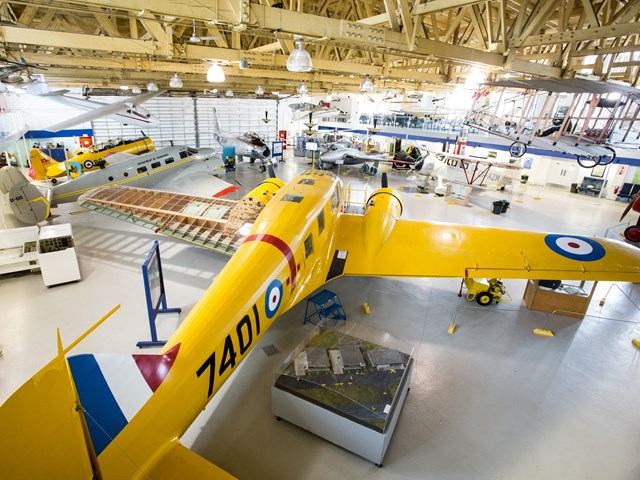Alt Text: Bright yellow WWII-era plane under restoration in hangar