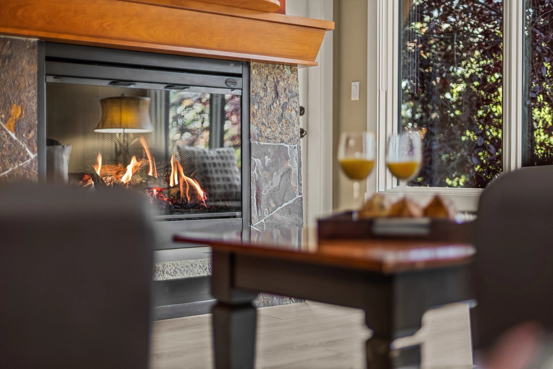 Lit stone fireplace beside a table with orange drinks and pastries.