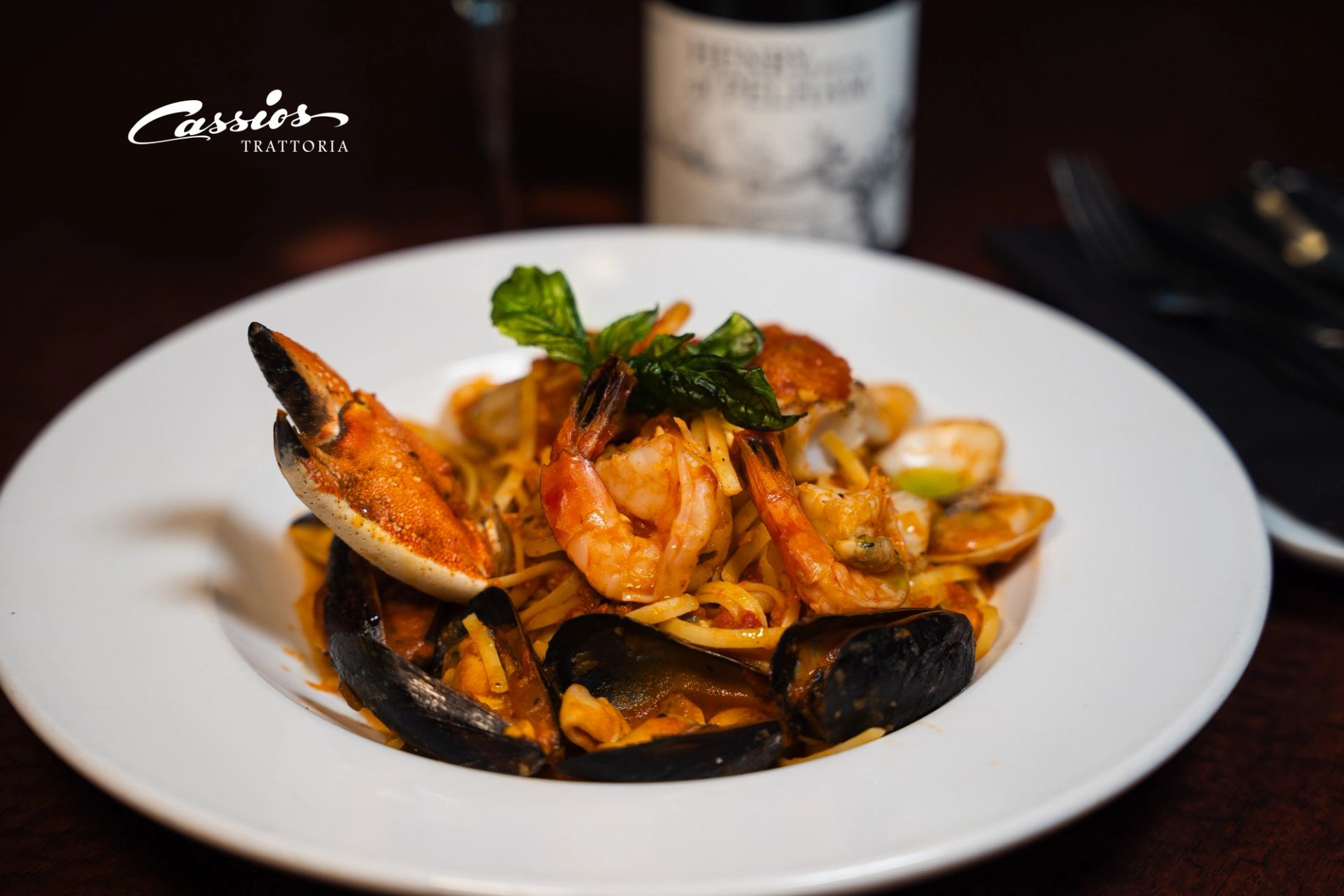 Seafood pasta with shrimp, mussels and crab claw on white plate at Cassios Trattoria.
