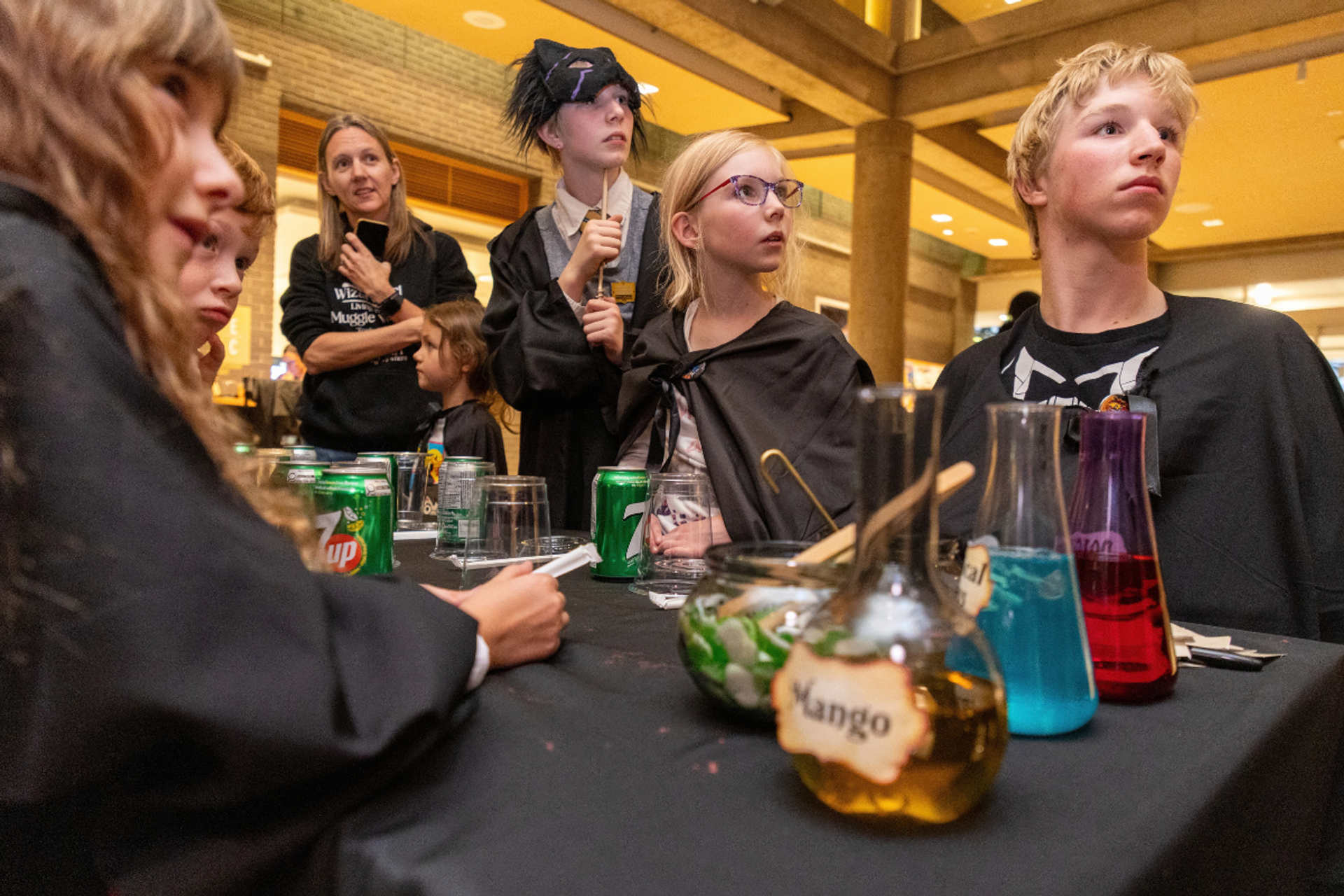 Costumed group gathers around a table with colourful drinks and potion jars.