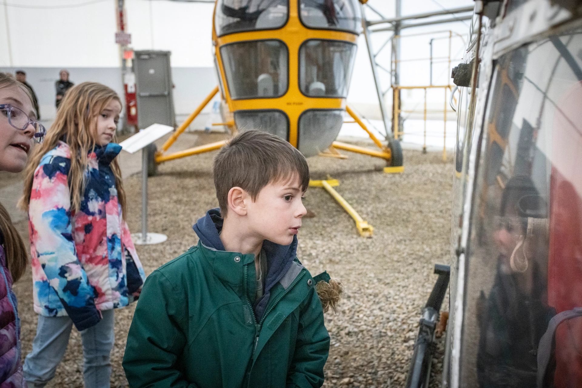 Helicopter cockpit doors open, with visitors standing nearby at Hangar Flight Museum in Calgary.