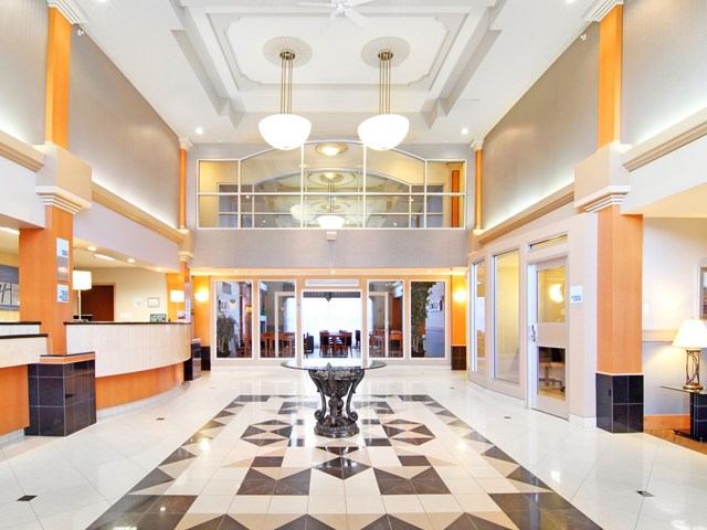 Spacious hotel lobby with fountain, reception desks, and large windows at Holiday Inn Express Calgary South.