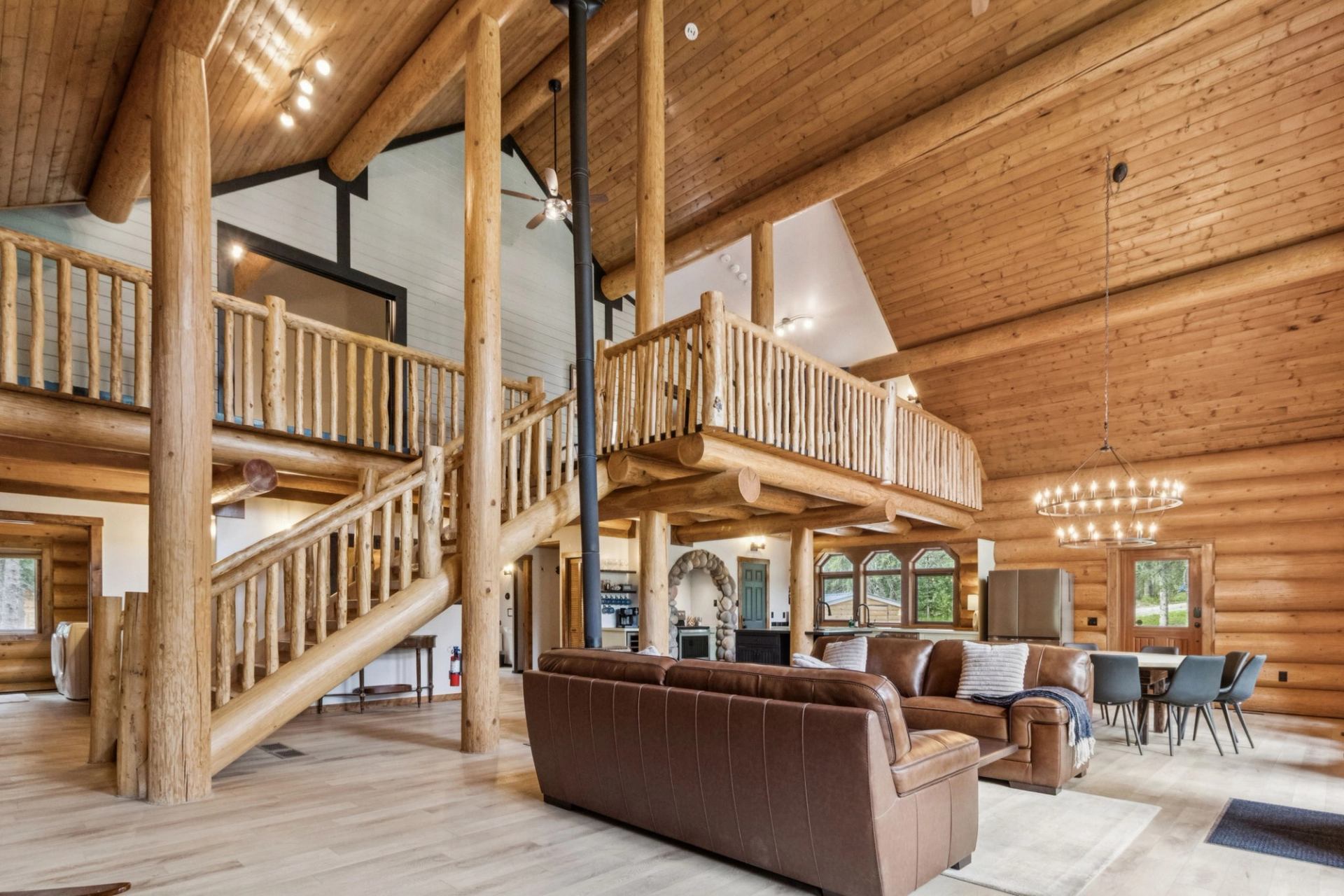 Spacious log cabin interior with loft, leather sofas, and wood beams.